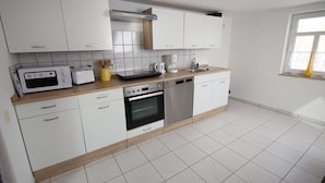 A modern kitchen with white cabinets, a microwave, toaster, coffee maker, and dishwasher. - Behagliche Ferienwohnung in Elbingerode (Oberharz am Brocken)