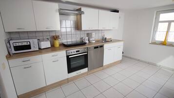 A modern kitchen with white cabinets, a microwave, toaster, coffee maker, and dishwasher.