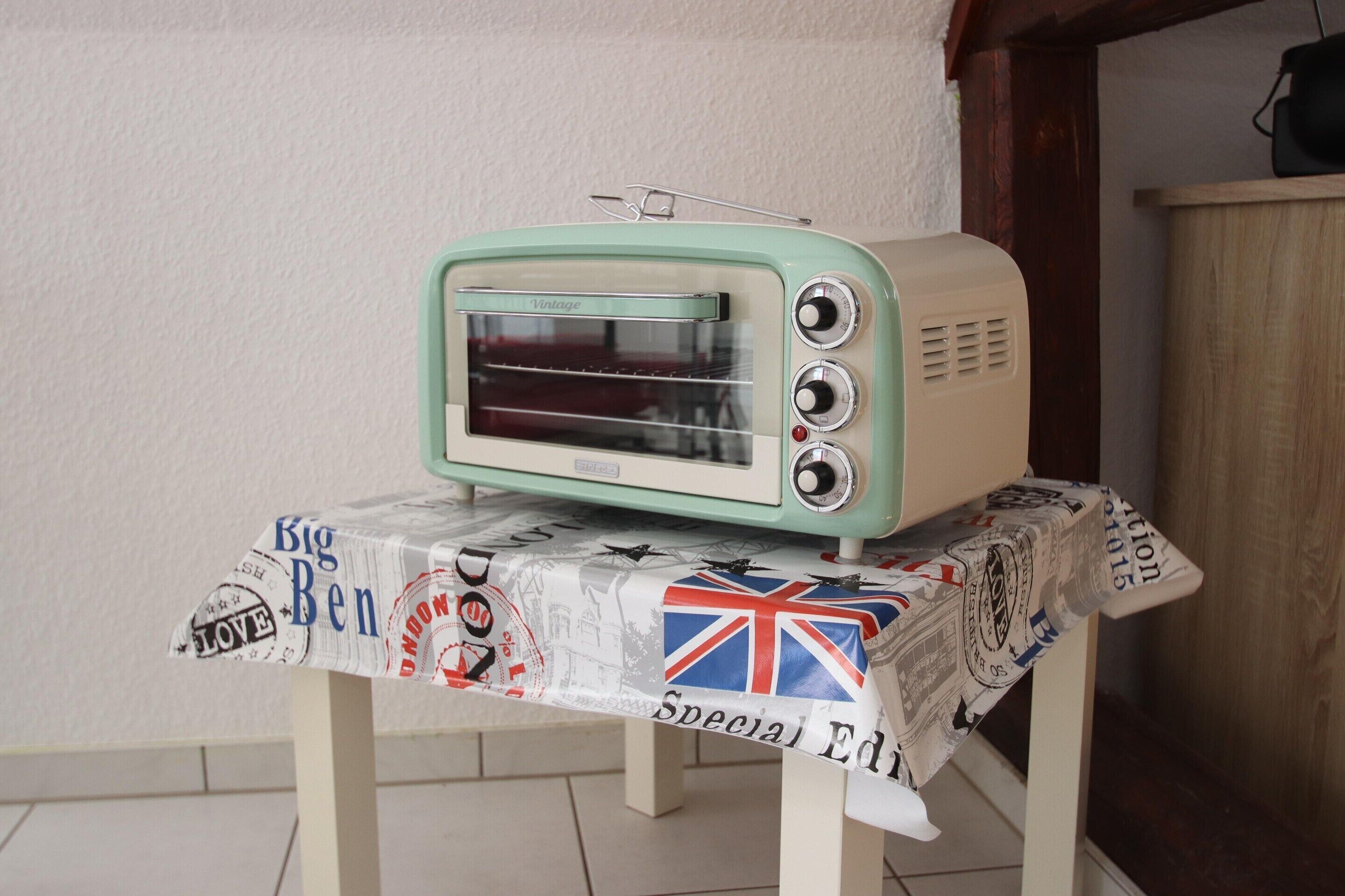 Un horno tostador antiguo sobre una mesa con mantel decorado con motivos de la cultura británica.