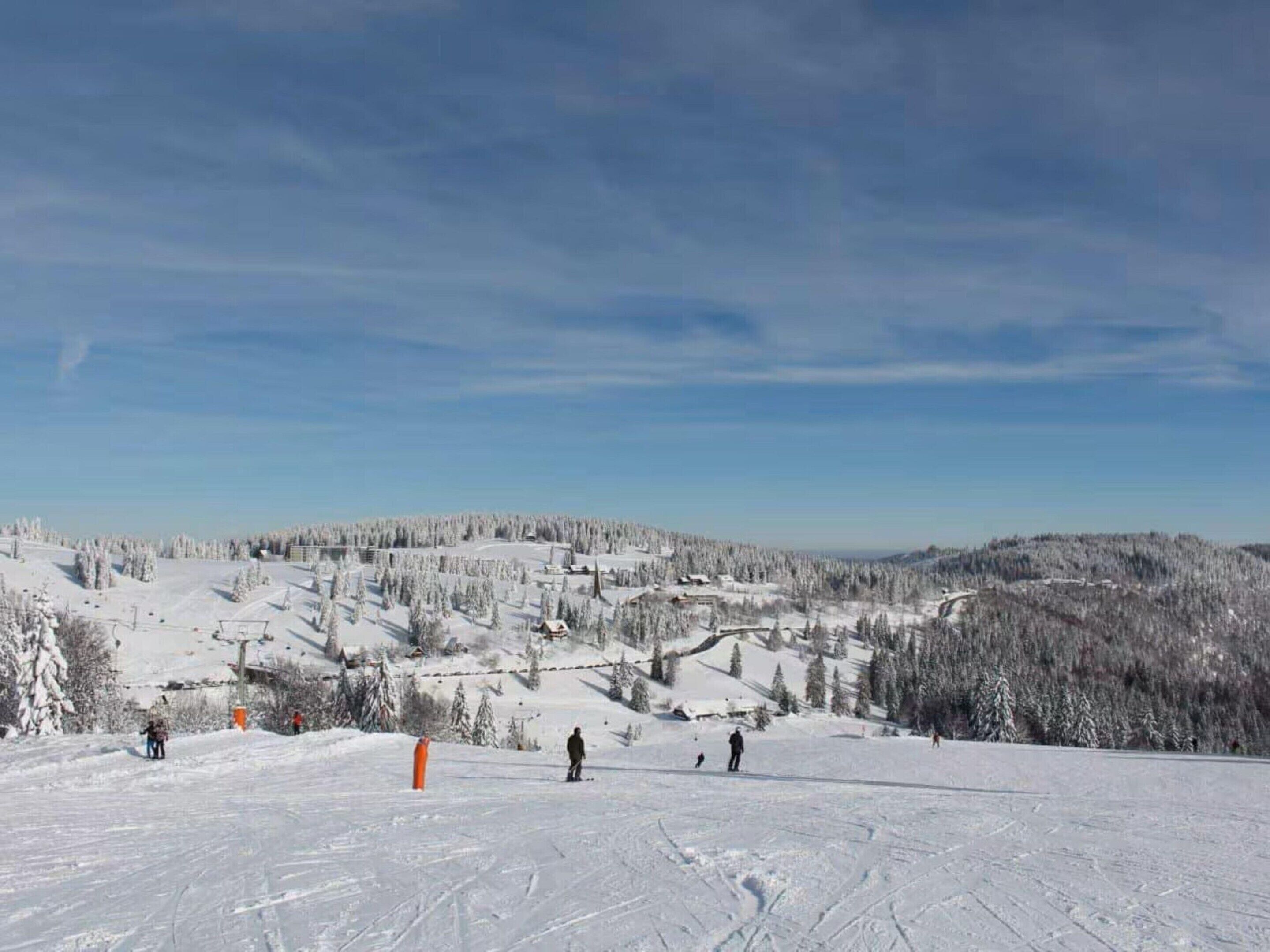 A snowy ski slope with skiers and a ski lift.