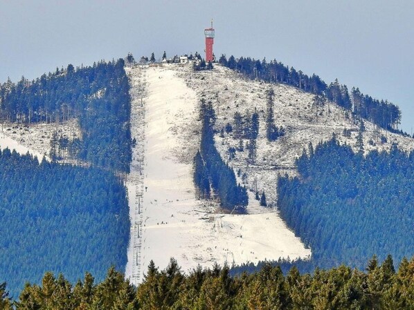 A snow-covered mountain with a ski lift and a red tower.