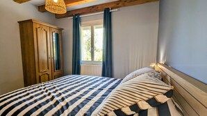 Ein Schlafzimmer mit einem großen Bett, einem Holzschrank und einem Fenster mit Vorhängen.