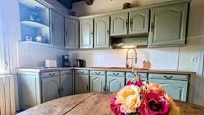Eine Küche mit hellgrünen Schränken, einem Holztisch und einer Vase mit Blumen.