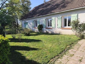 A house with a sloped roof, multiple windows with shutters, and a well-maintained lawn. - Charming Countryside Getaway: Spacious Home with Private Garden and Easy Access to Local Attractions (Arthon)