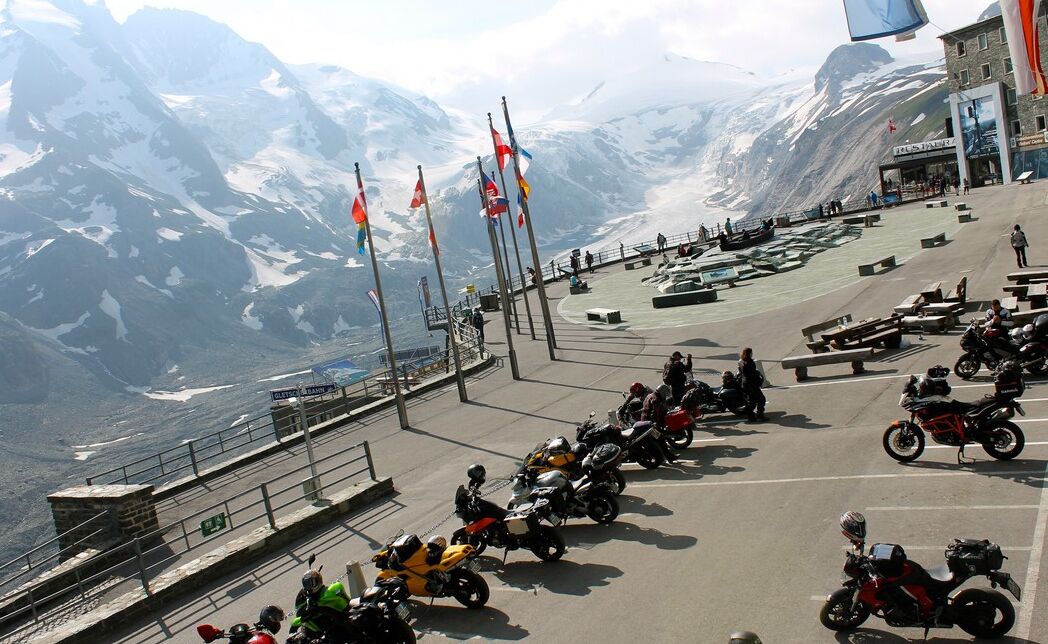 Une vue sur la montagne, avec des drapeaux, un café et des motos garées.