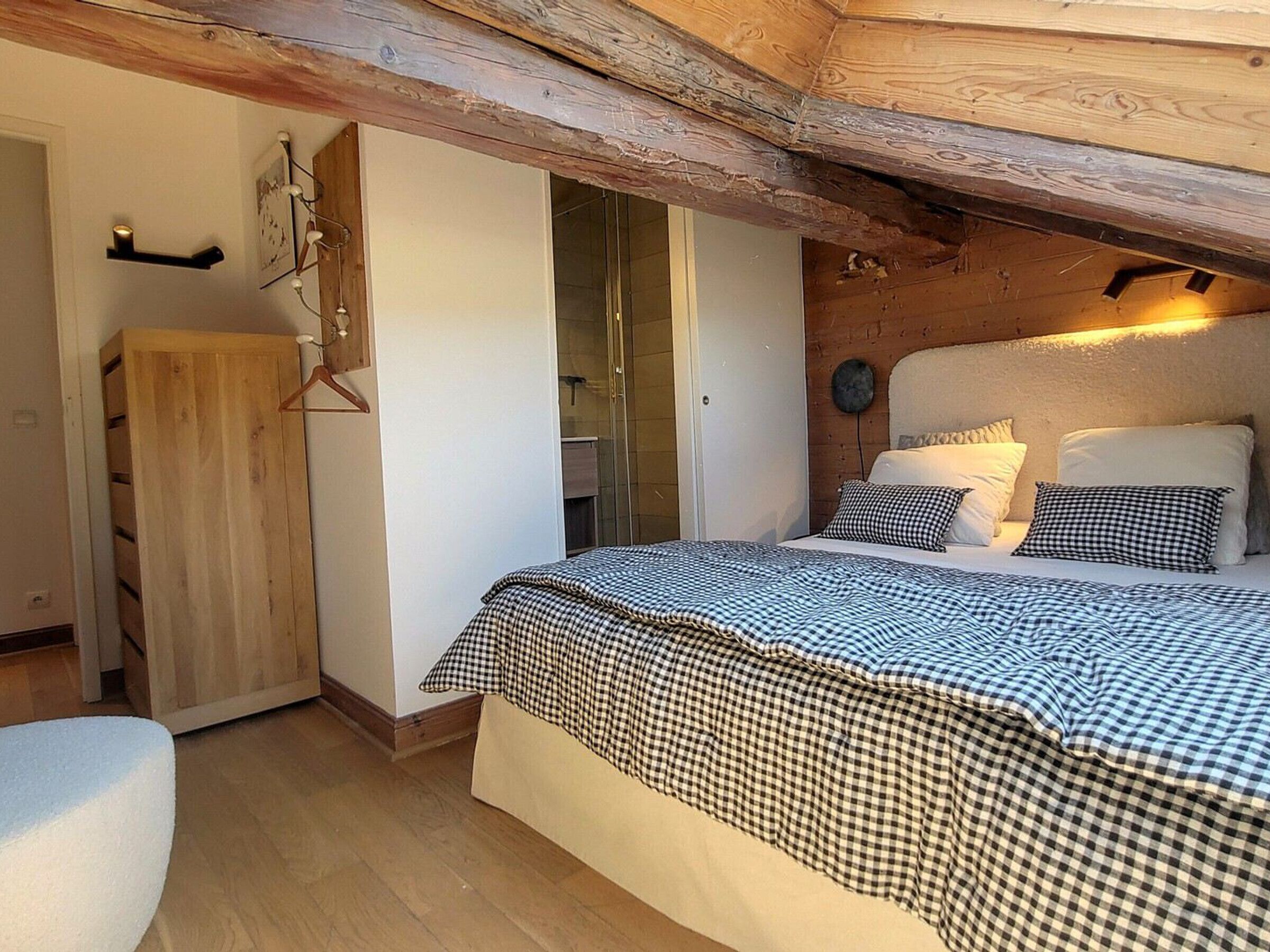Une chambre à coucher comprenant un lit, une armoire en bois et une autre armoire avec un miroir, ainsi qu’une porte donnant accès à la salle de bain.