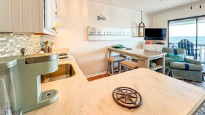 A modern kitchen with a large island, a dining area with a view, and a cozy seating area with a view. - Blue Pearl Oceanfront Modern at Sea Cabin w Pool (North Myrtle Beach)