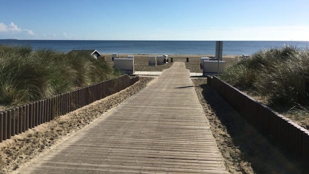 A wooden boardwalk leading to beach huts, surrounded by dunes. - Coastal Love in Karlshagen (Karlshagen)