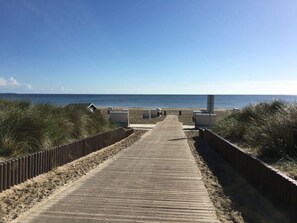 A wooden boardwalk leading to beach huts, surrounded by dunes. - Coastal Love in Karlshagen (Karlshagen)