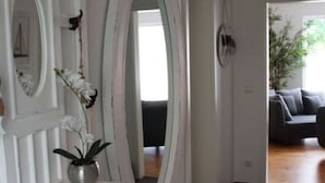 A white vanity with an oval mirror, a small stool, and a potted orchid. - Coastal Love in Karlshagen (Karlshagen)