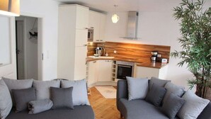 A modern living room with two grey sofas, a wooden floor, and a kitchen in the background. - Coastal Love in Karlshagen (Karlshagen)