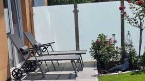 A patio with two sun loungers, a small table, and a white wall. - Coastal Love in Karlshagen (Karlshagen)