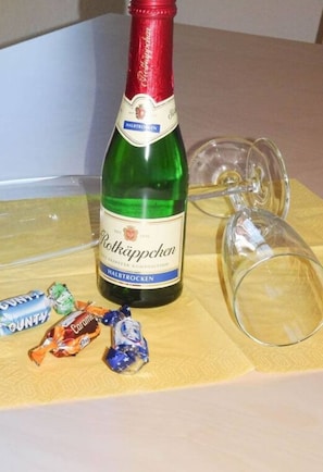 Une bouteille de Rötkäppchen Halbstarken, deux verres à vin vides et quelques emballages de bonbons sur une table.