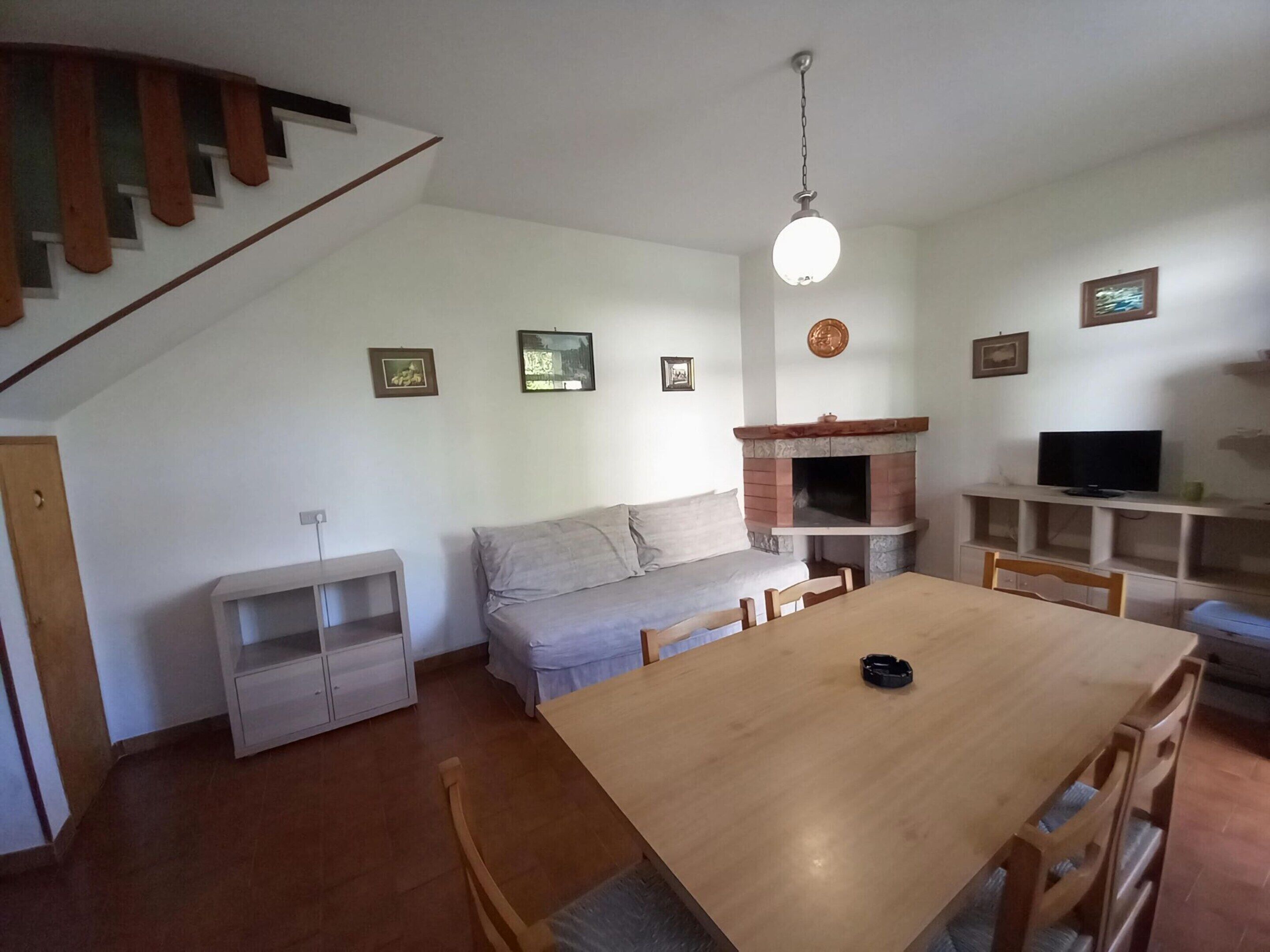 A cozy living room with a wooden dining table, a sofa, and a fireplace.