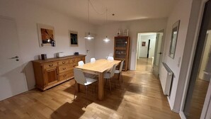 Un vaste espace dédié à la salle à manger, avec une table et des chaises en bois, un buffet en bois et des luminaires suspendus.