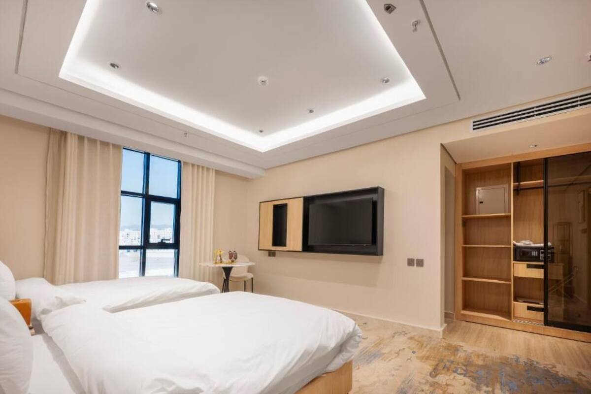 A hotel room with two beds, a TV, a desk, and a wardrobe.