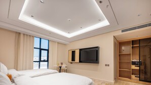 Una habitación de hotel moderna con dos camas, televisión, escritorio y un amplio armario.