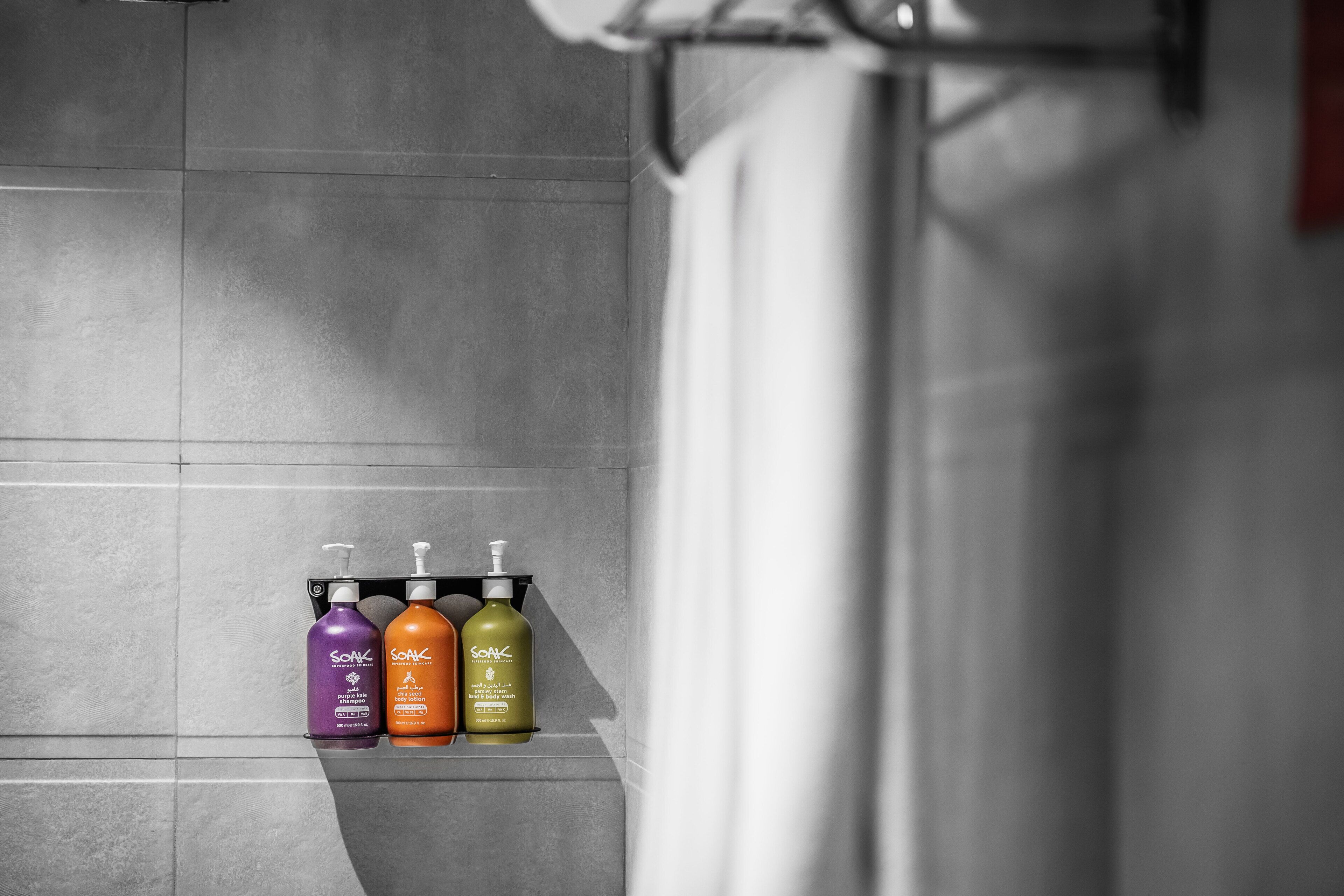Ein Badezimmer mit drei Flaschen Soak-Shampoo an einer gefliesten Wand.