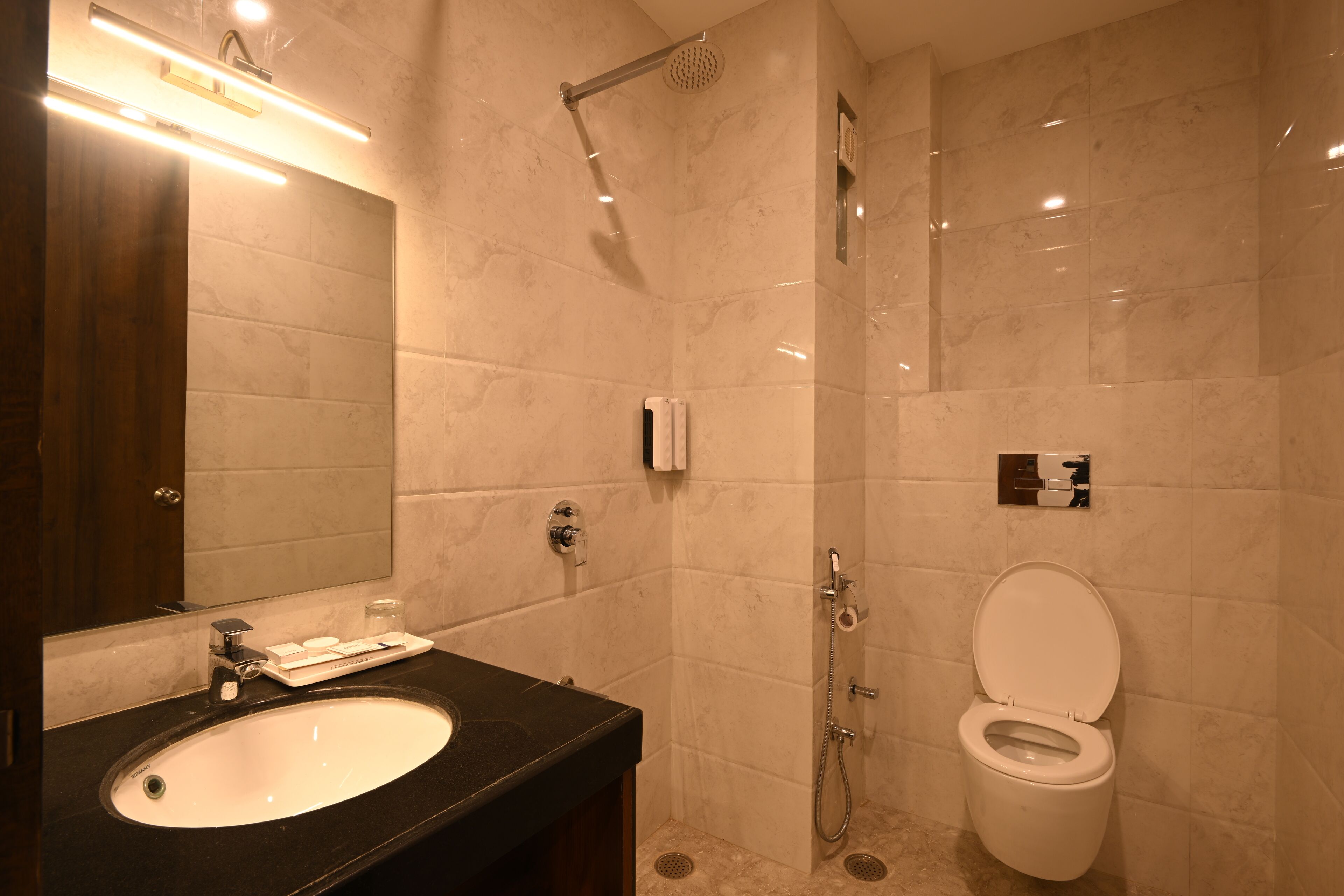 Un baño moderno con un lavabo negro, un espejo, una ducha y un inodoro.