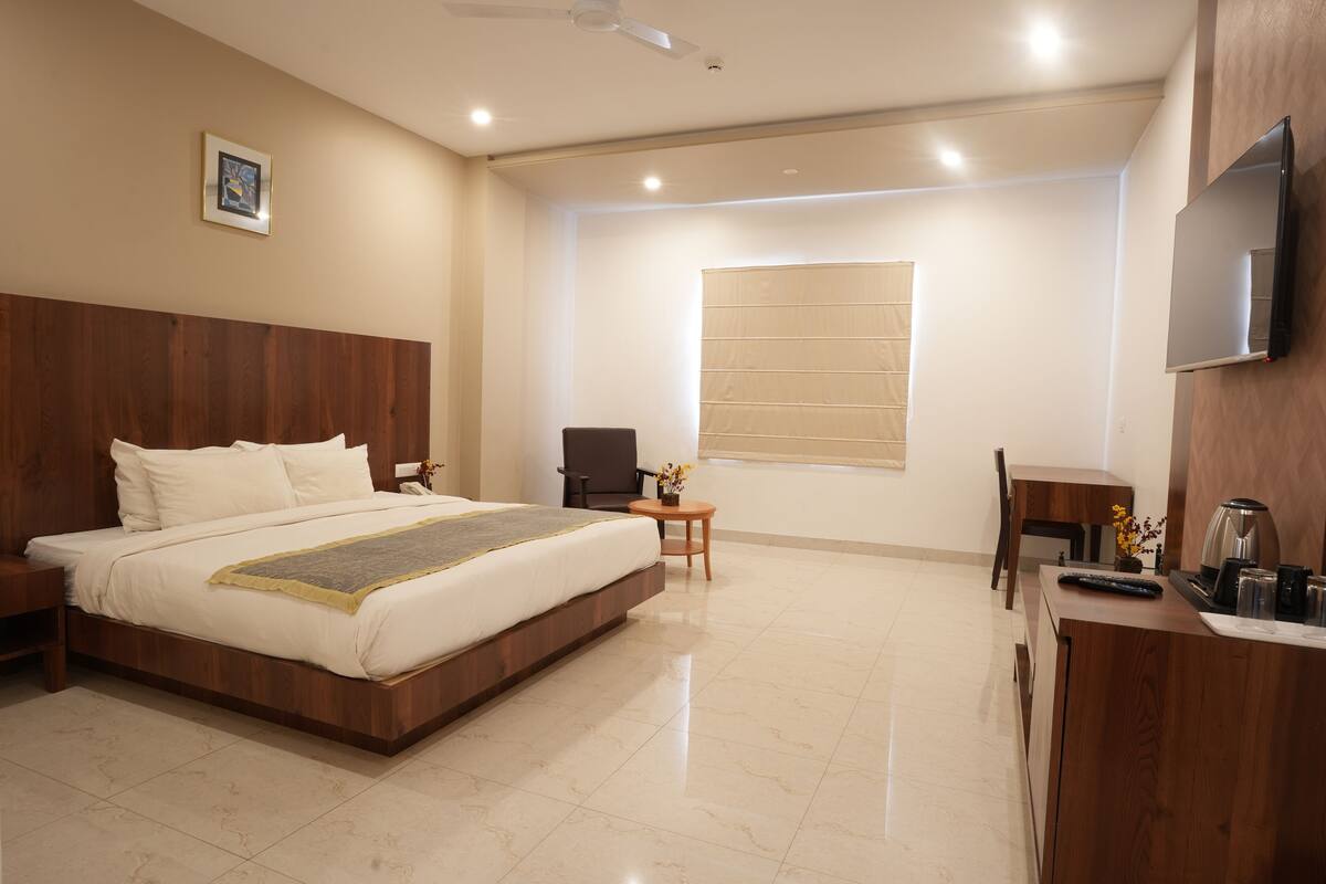 Une chambre d’hôtel moderne équipée d’un grand lit, d’un bureau, d’une chaise et d’un téléviseur fixé au mur.