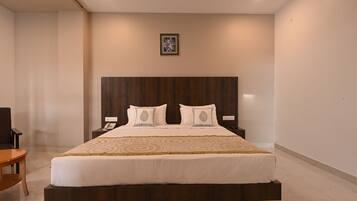 Una habitación de hotel moderna con una cama grande, cabecera de madera y una mesita de noche con un teléfono.