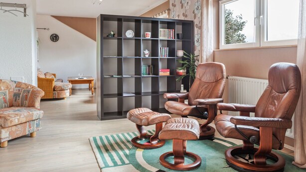 A living room with a sofa set, a leather armchair, a wooden coffee table, and a bookshelf. - Apartment in Bad Wunnenberg Near Ski Willingen (Bad Wuennenberg)