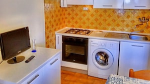 Une cuisine compacte équipée d’une cuisinière à gaz, d’un four et d’un lave-linge.