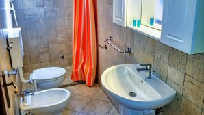 Une salle de bain avec deux toilettes, un lavabo, une douche et une fenêtre.