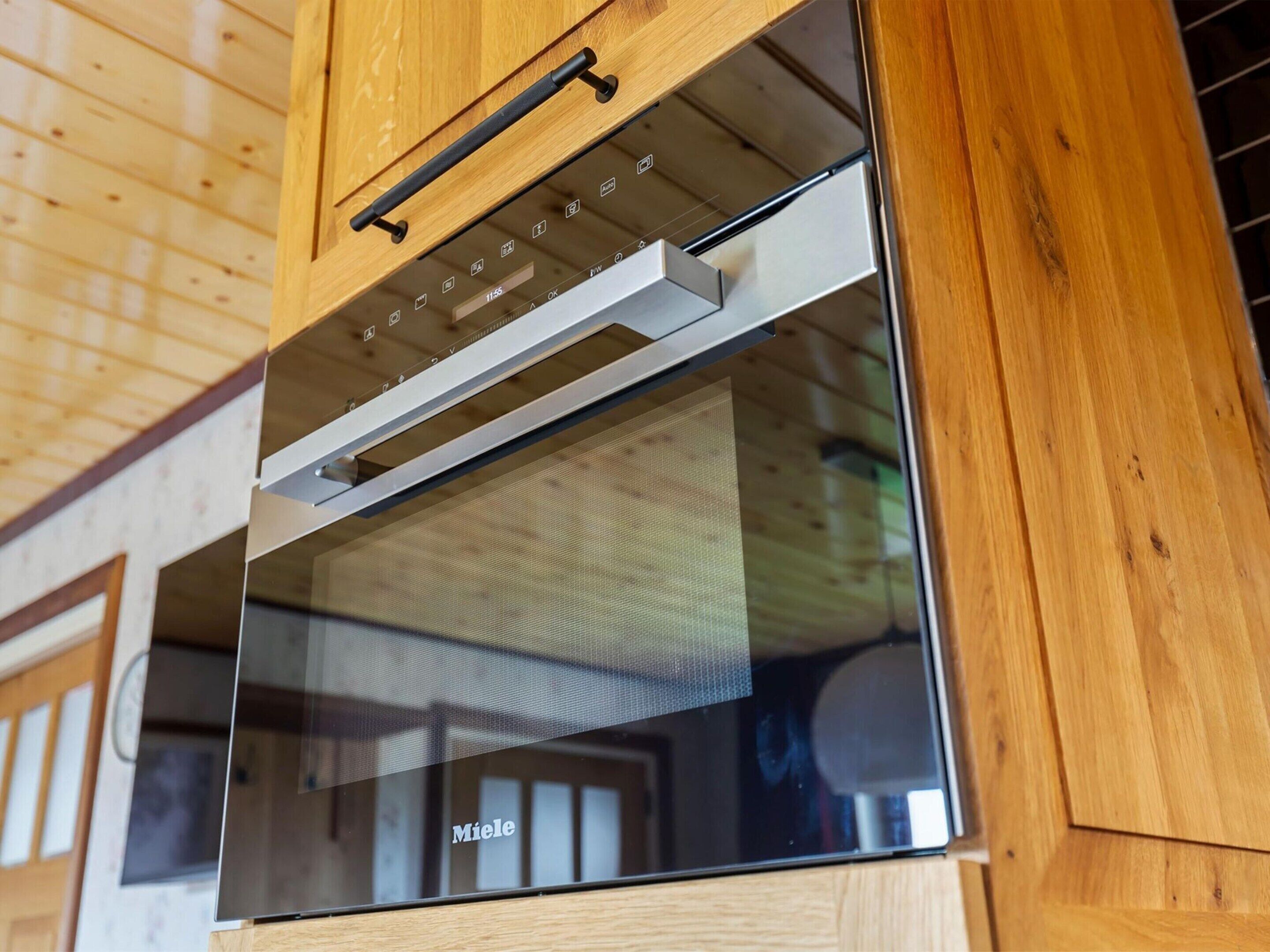 A modern kitchen with a built-in oven and a wooden cabinet above it.