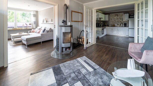 Un amplio salón con chimenea, un sofá, una mesa de centro y una cocina al fondo.