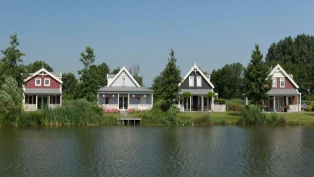 A row of three houses by a lake with a dock. - Holiday Home in South Holland Near Rotterdam (Simonshaven)