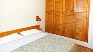 A bedroom with a wooden wardrobe, a bed with a floral bedspread, and a wall-mounted light fixture. - Attractive Villa With Garden (Ravenna)