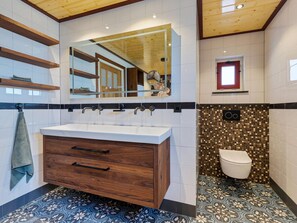 Une salle de bain moderne avec un meuble-lavabo en bois, un grand miroir et un carrelage décoratif.
