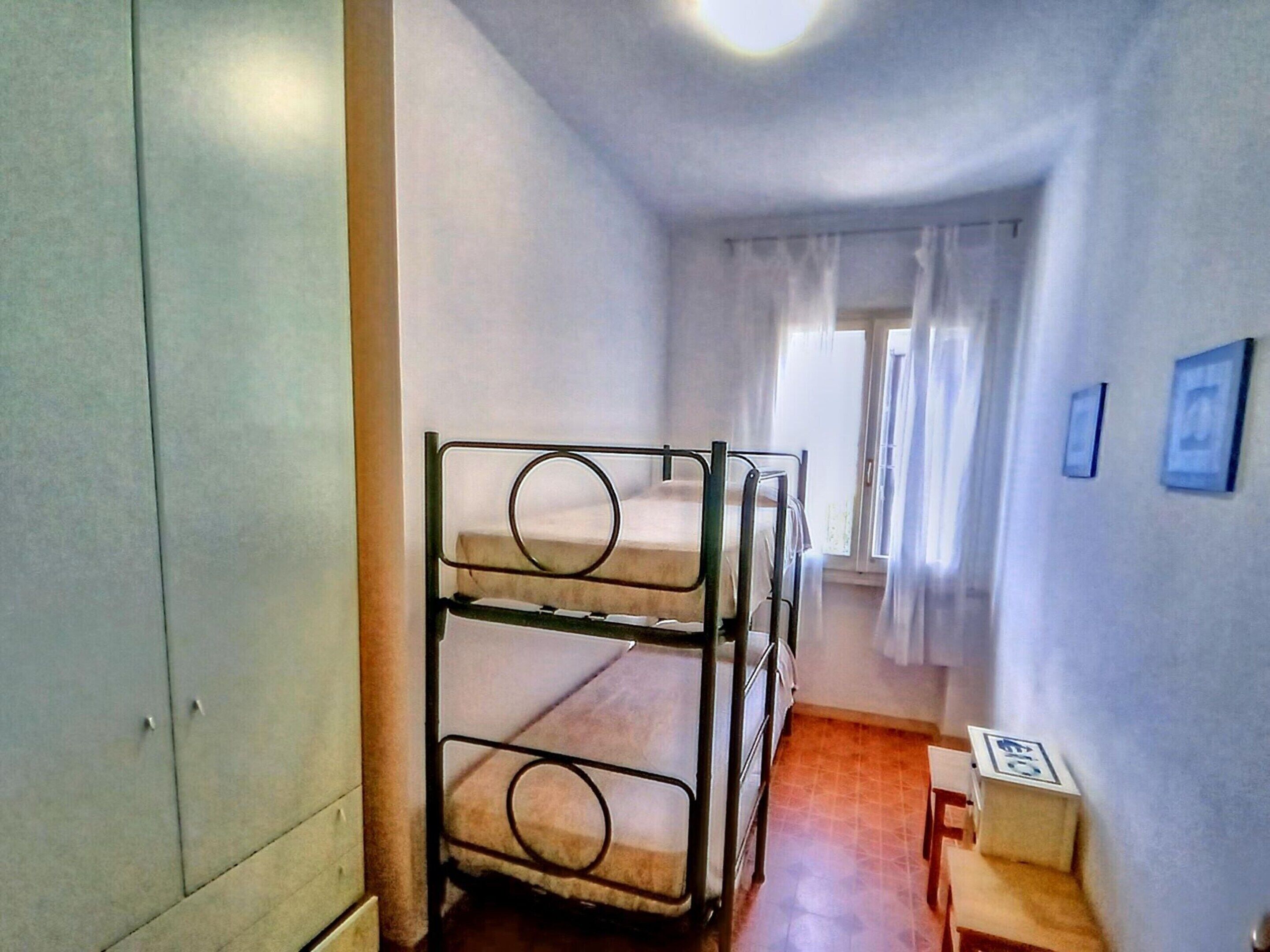 Un lit superposé dans un couloir étroit, avec une fenêtre et une petite table.