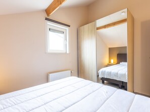 Quarto com cama, janela, radiador e espelho.