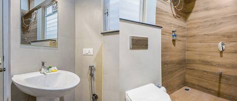 A bathroom with a sink, mirror, shower, and toilet.