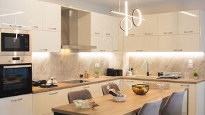 A modern kitchen with a central island, built-in appliances, and contemporary lighting fixtures. - Stergiosapartment in Volos (Volos)