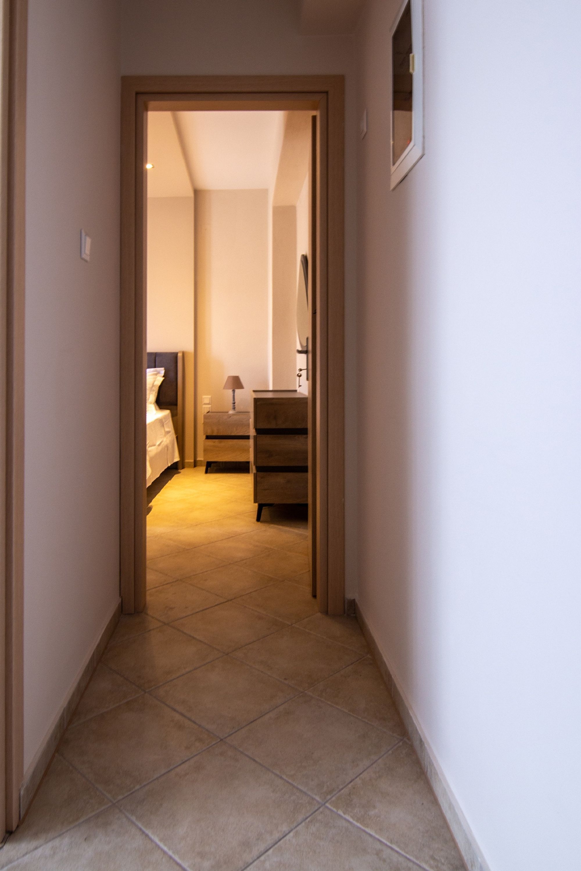 A narrow hallway with a bed and dresser visible in the background.