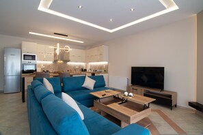 A modern living room with a blue sofa, a wooden coffee table, and a TV. - Stergiosapartment in Volos (Volos)