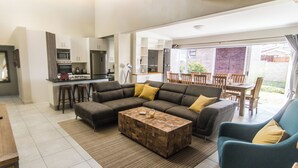 Una sala de estar moderna con un sofá modular, una mesa de centro de madera y un comedor con mesa y sillas.