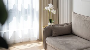 Ein modernes Wohnzimmer mit einem beigen Sofa, einem kleinen Beistelltisch und einer Topf-Orchidee.