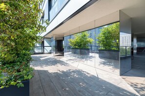 A modern building with large glass windows, a flat roof, and a wooden deck. - RentPlanet - Apartament Grzybowska (Warsaw)