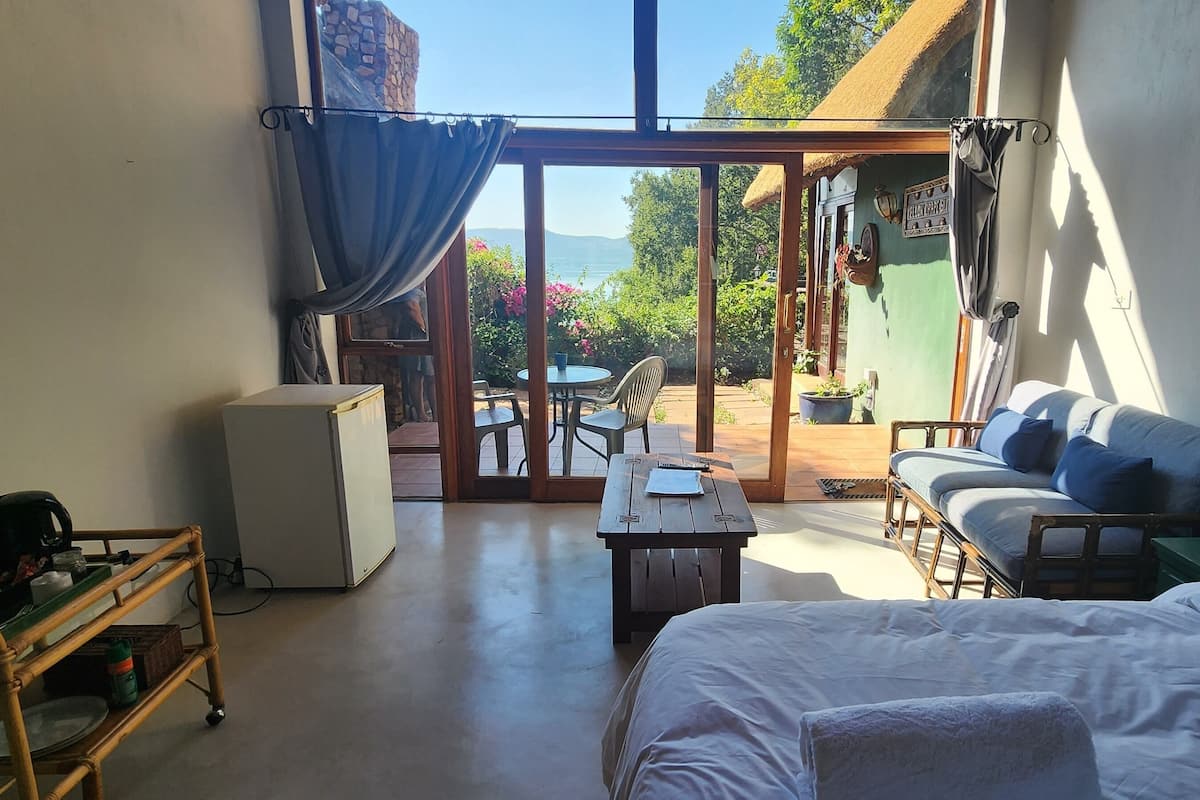 Una habitación con cama, escritorio, silla, mesa y vistas al exterior.