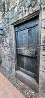 Una puerta de madera rústica con textura desgastada, incrustada en un muro de piedra.