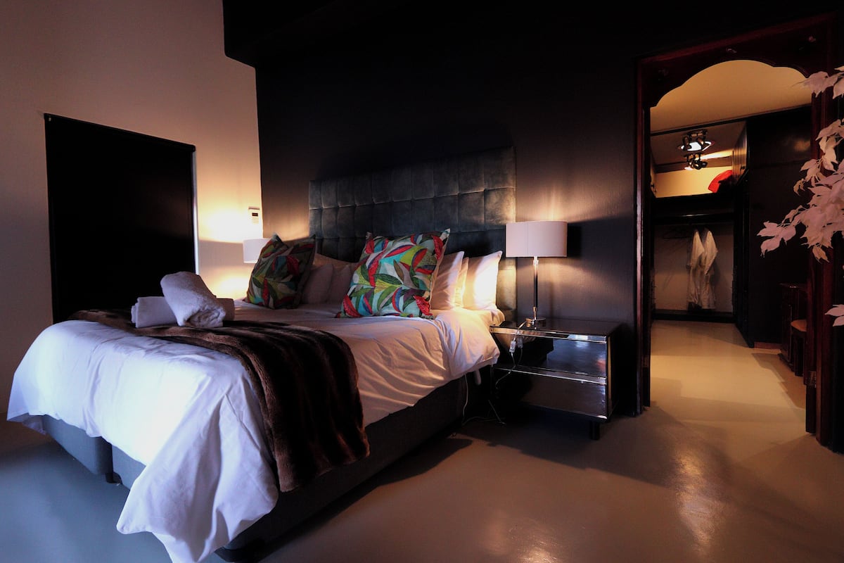 Un dormitorio moderno con una cama grande, una mesita de noche y un buró.