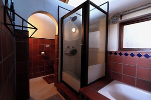 Un baño con ducha envuelta en cristal, bañera y ventana.