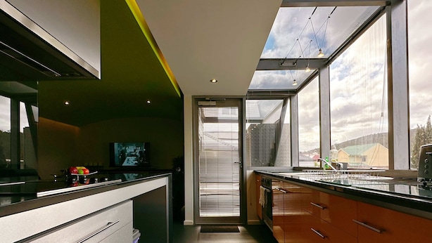 A modern kitchen with a skylight, a television, and a window with blinds.