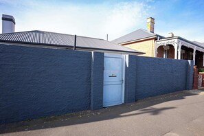 Un immobile residenziale con una parete blu a rilievo, una porta metallica e una casa in mattoni con un camino.
