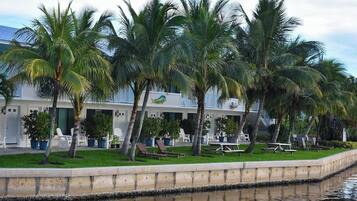 A resort with palm trees, a pool, and a building with a balcony.