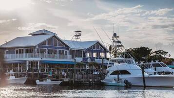 A waterfront building with a dock, boats, and a clear sky.